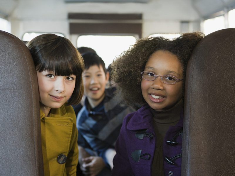 Friends sharing a happy moment on a school bus journey.