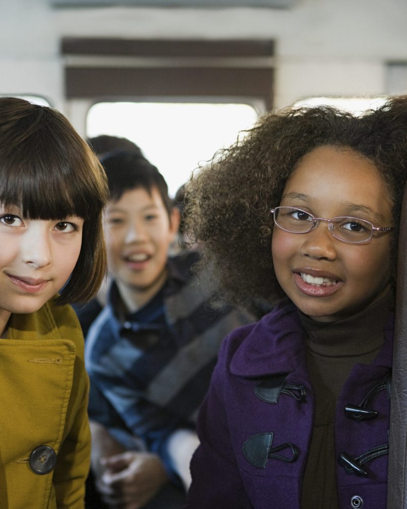 Friends sharing a happy moment on a school bus journey.