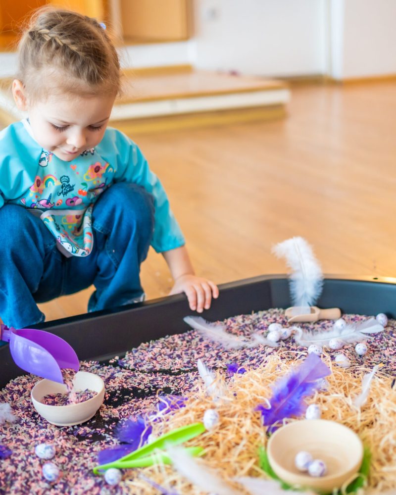 Little girl playing with sensory colorful rice. Sensory development and experiences, themed activities with children, fine motor skills development. High quality photo